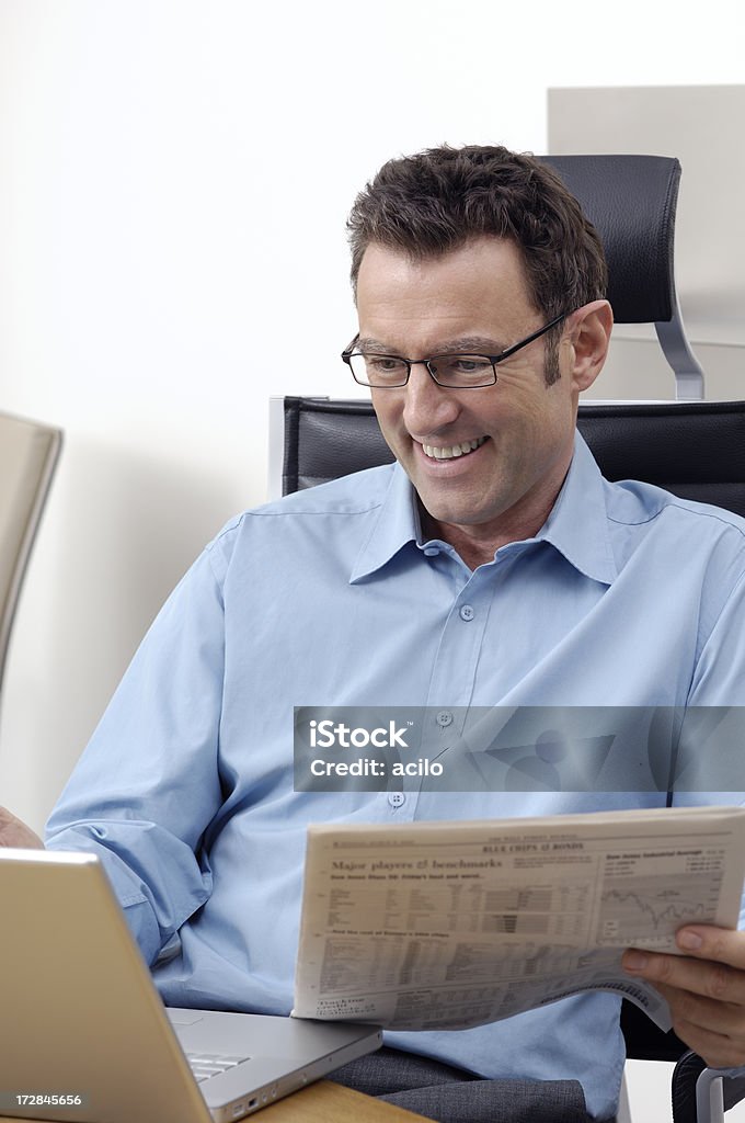 Smiling businessman Businessman comparing the informations on his laptop with a financial newspapaer. 30-39 Years Stock Photo