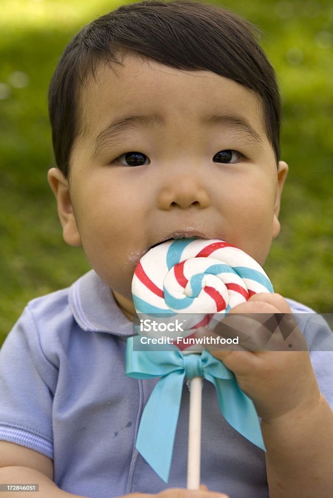 Bambino asiatico, coreano bambino mangiare Lecca-lecca di zucchero - Foto stock royalty-free di Erba