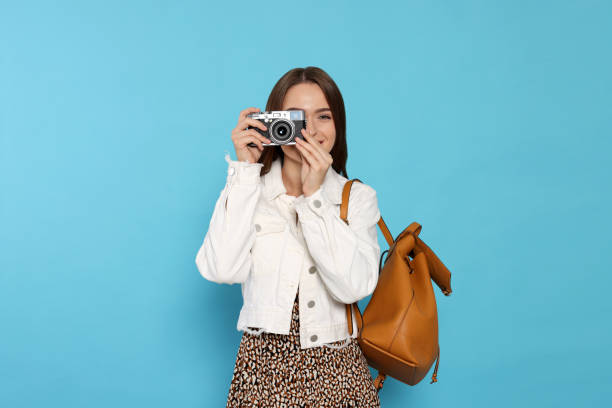 istock Young woman with camera taking photo on light blue background. Interesting hobby 1728463737