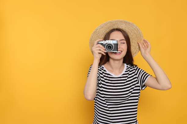 istock Young woman with camera taking photo on yellow background, space for text. Interesting hobby 1728465906