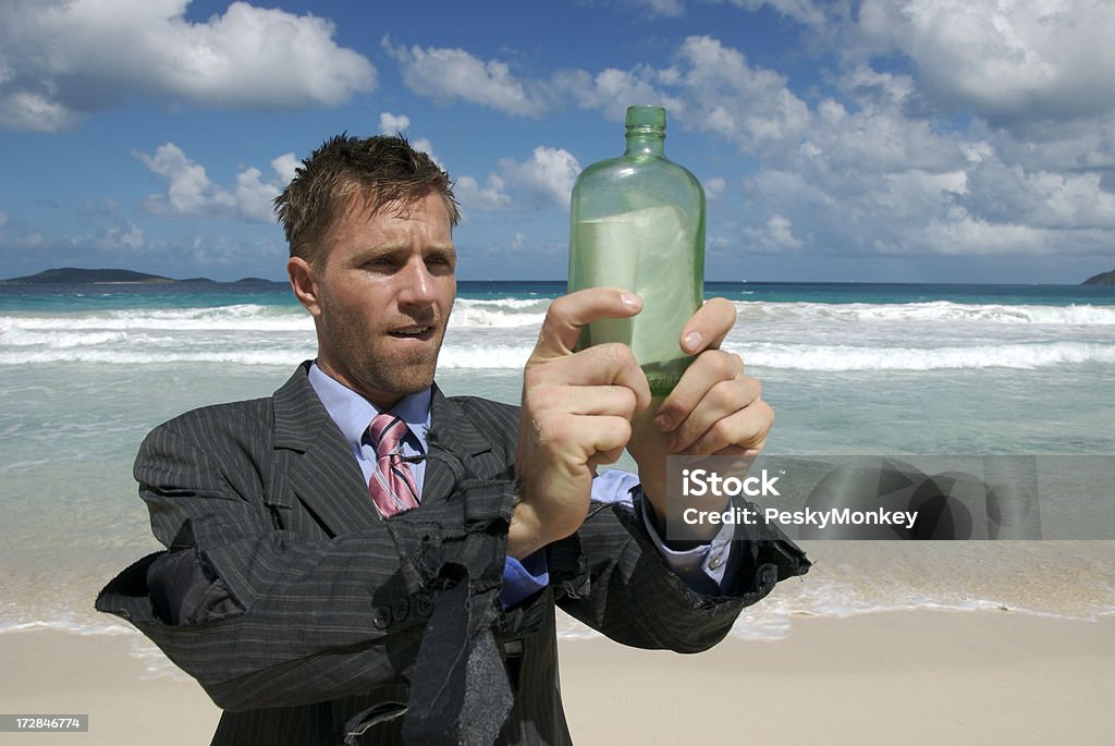 Изгой бизнесмен, держа Послание в бутылке на тропический Пляж - Стоковые фото SOS - английское слово роялти-фри
