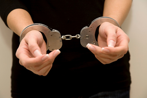 Female with manicured nails handcuffed.