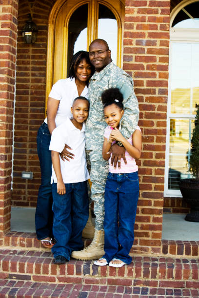 A family standing together on the front steps of their home stock photo
