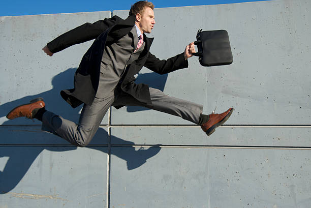 istock Businessman in Full Suit Jumping Outdoors Gray Wall Background 172848023