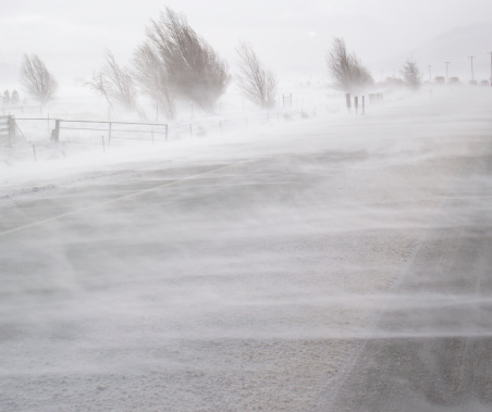 Snow blowing over road in blizzard conditions.
