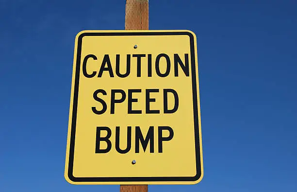 Yellow Caution Speed Bump Sign, horizontal photo with attractive blue sky background.