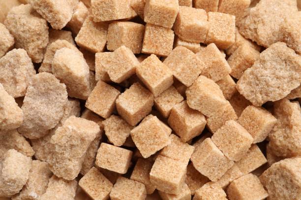 istock Different pieces of refined brown sugar as background, closeup 1728502734