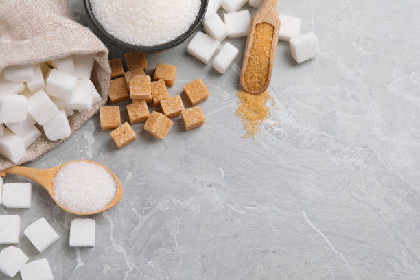 istock White and brown sugar on light grey marble table, flat lay. Space for text 1728503819