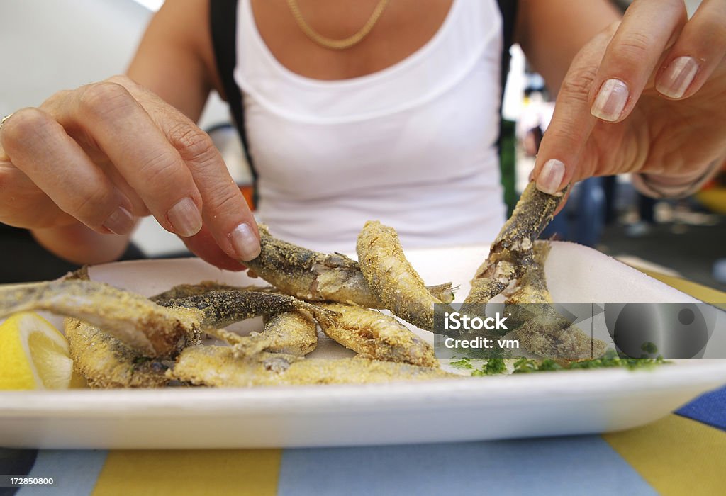 Healthy eating Woman eating fried fish in street restaurant. Eating Stock Photo