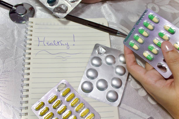 Medicines, pills, stethoscopes and a notebook with the word ''healthy'' written on it. Photo taken at the dining room table
