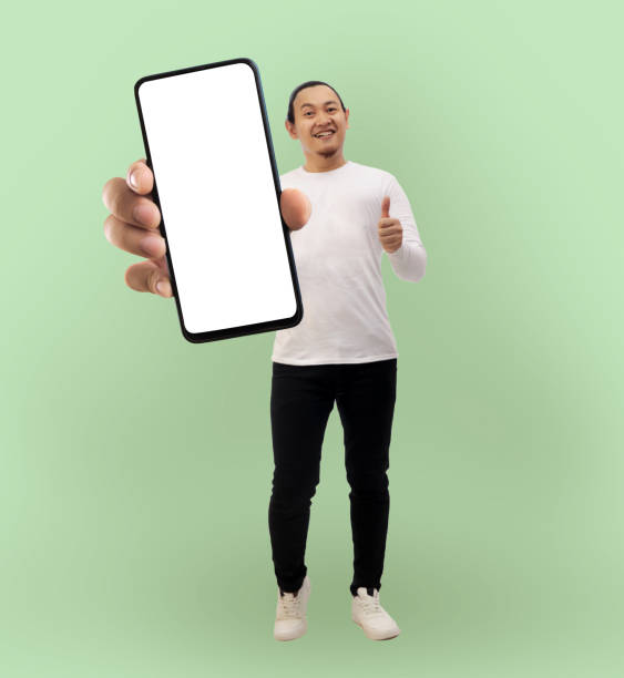 istock Asian man looking to camera, smiling and showing empty blank white copy space phone mock up template 1728549481