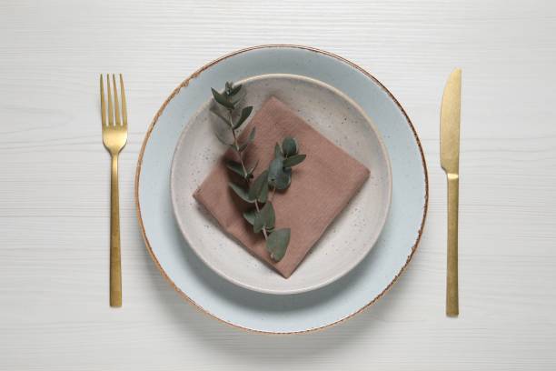 istock Stylish setting with cutlery and eucalyptus leaves on white wooden table, flat lay 1728563713