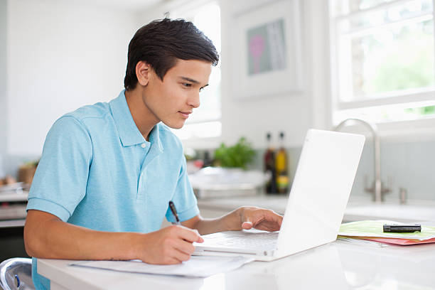 garoto adolescente usando o laptop e fazendo lição de casa - high school student student computer laptop - fotografias e filmes do acervo