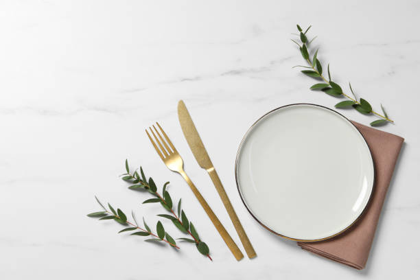 istock Stylish setting with cutlery and eucalyptus leaves on white marble table, flat lay. Space for text 1728571752