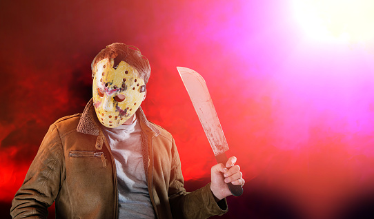 man in maniac movie hockey mask and machete in halloween costume on friday