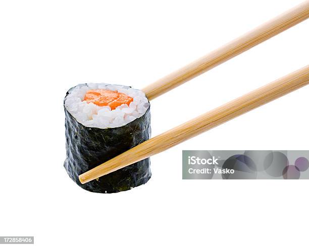 A Sushi Roll With Salmon Being Held By Wooden Chopsticks Stock Photo - Download Image Now