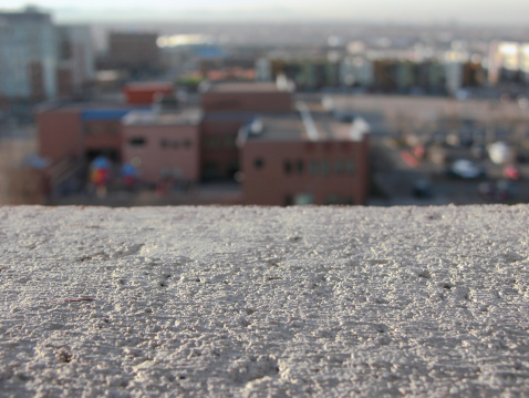 viewpoint of person standing on the edge of a tall building looking over the city below