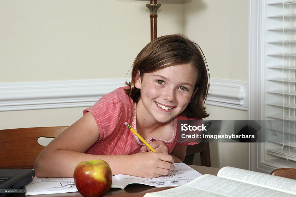 School Homework  See others from this series Child doing homework with apple in foreground for a snack. 10-11 Years Stock Photo