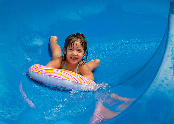 Summer Pool Sliding a girl having fun sliding down a water slide with a big smile. girls laying on beach stock pictures, royalty-free photos & images
