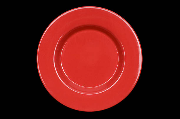 Whole red dinner plate centered on black stock photo