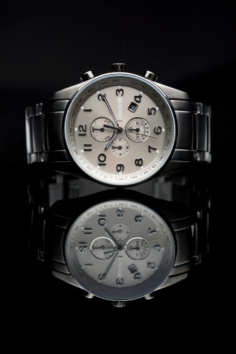 A very expensive, luxury watch lying on a black glass. Beautiful reflection. Typical luxury image.