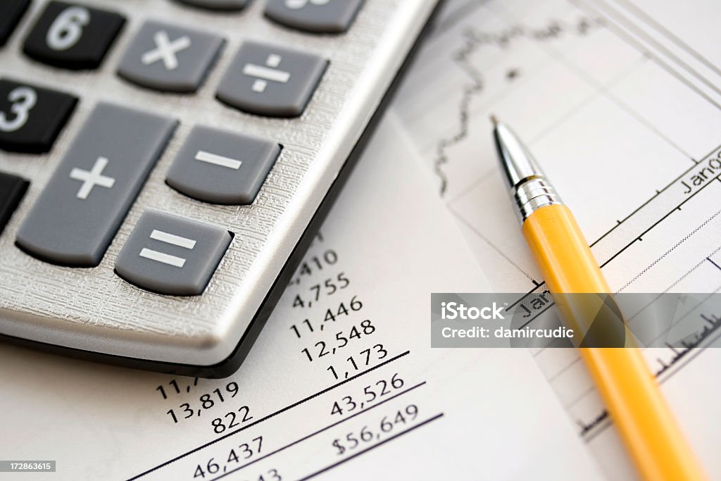 A calculator on top of some financial data Financial data Analyzing Stock Photo