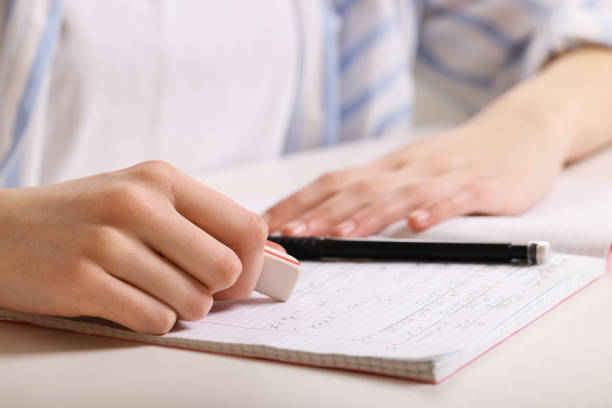 istock Girl erasing mistake in her notebook at white desk, closeup 1728643201