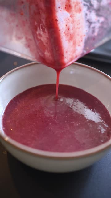 Cook pouring the acai smootie just out of the blender into a bowl. Preparation of acai bowl