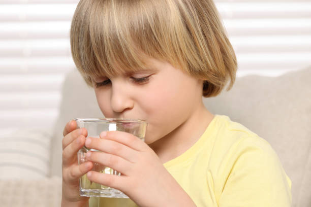 istock Cute little boy drinking fresh water from glass indoors 1728644092