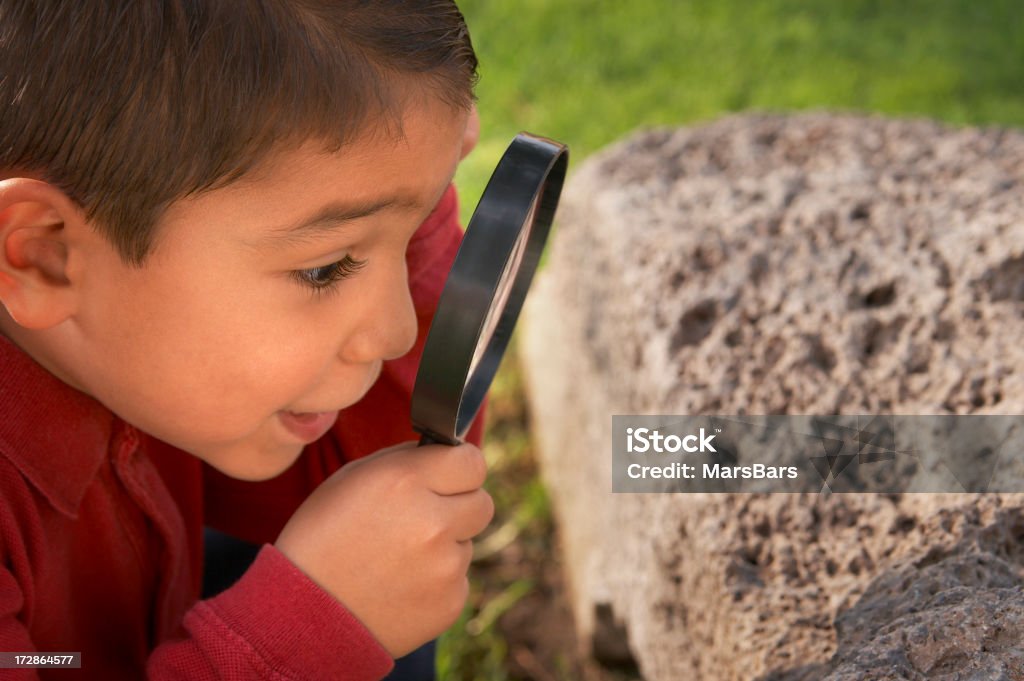 Ragazzo guardando attraverso la lente d'ingrandimento - Foto stock royalty-free di Bambino