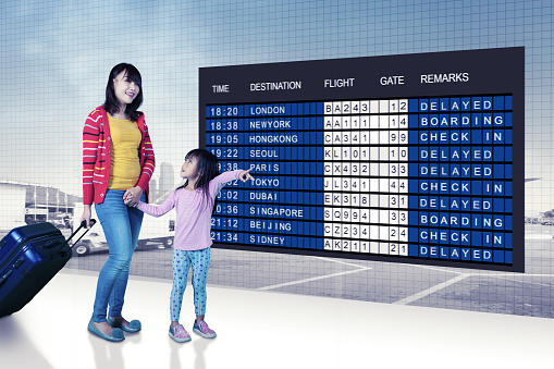 Mother and daughter pointing and looking at the flight information board