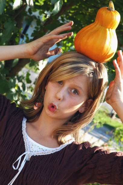 Thirteen-year-old girl makes a funny face as she poses with an odd pumpkin.