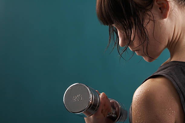 Close up of a woman sweating in the gym doing weights stock photo