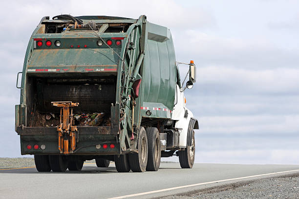 Image of a garbage truck driving down a road  stock photo