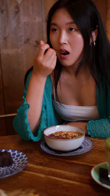 Shot of a young woman scooping a spoonful of an acai bowl with raspberry and granola