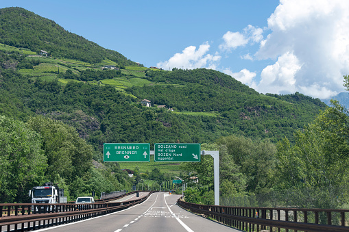 Bolzano, Italy-June 13, 2023; Driver’s perspective view over the Autostrada A22 motorway through the Brenner Pass with signs overhead towards Austria and Brenner Pass and exit Bolzano