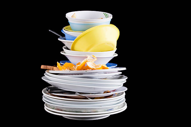 Pile of dirty dishes with an orange rind and rotting food A stack of dirty dishes on black. washing dishes stock pictures, royalty-free photos & images