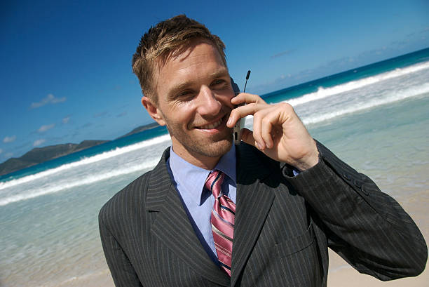 sonriente hombre de negocios hablando por teléfono móvil playa tropical - stranded men telephone beach fotografías e imágenes de stock