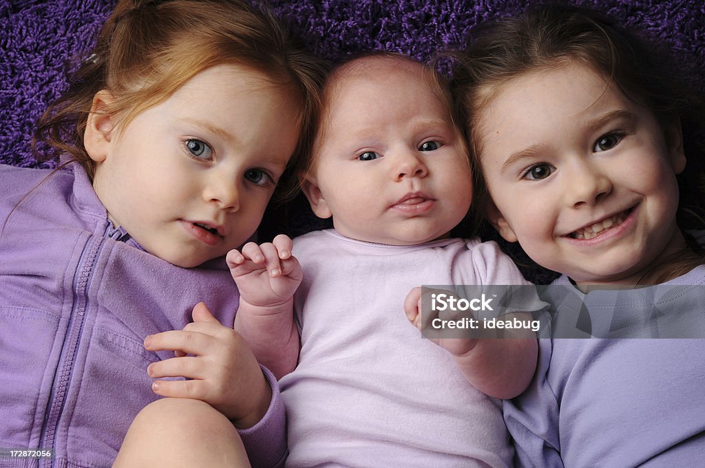 Tre sorelle Sdraiato su un tappeto viola - Foto stock royalty-free di Bebé