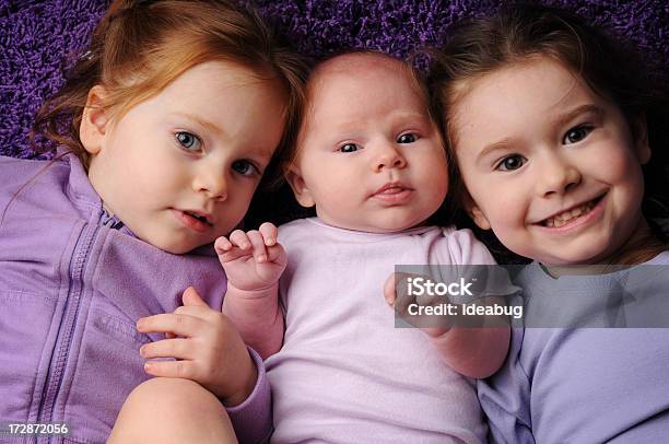 Tre Sorelle Sdraiato Su Un Tappeto Viola - Fotografie stock e altre immagini di Bebé - Bebé, Viola - Colore, Bambine femmine