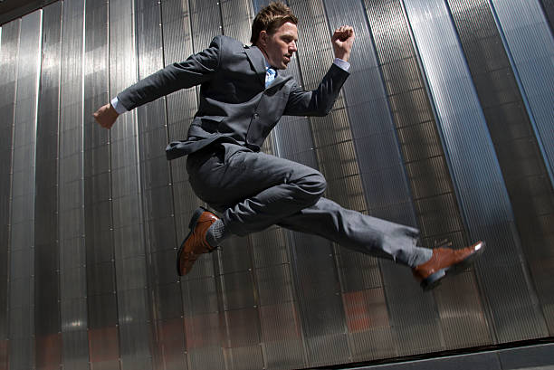 istock Businessman Jumping Outdoors Against Modern Shiny Silver Wall 172873783