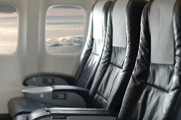 Aircraft seats and windows with cloudy view.