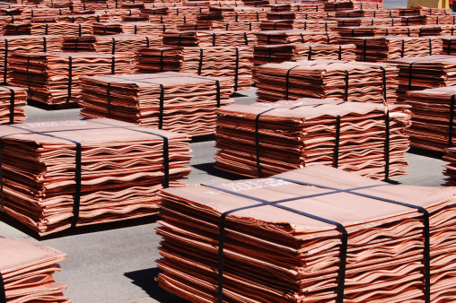 Sheets, or cathodes, of 99.99% pure copper sit in stacks outside a solvent-extraction plant awaiting shipment. Each stack is strapped with steel and arranged in neat piles which fill the image. Each stack is worth $15,000. 