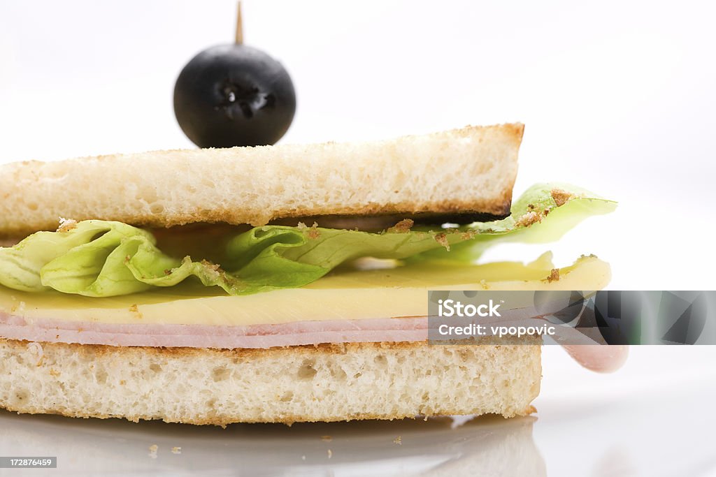 Club Sandwich "Side view of club sandwich, shallow dof, high key. Ingredients: toast, ham, cheese, lettuce and olive on top." Club Sandwich Stock Photo