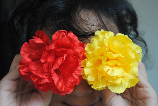 Girl is holding artificial red and yellow rose flowers.