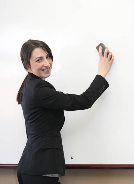 A smiling business woman erasing a whiteboard. stock photo