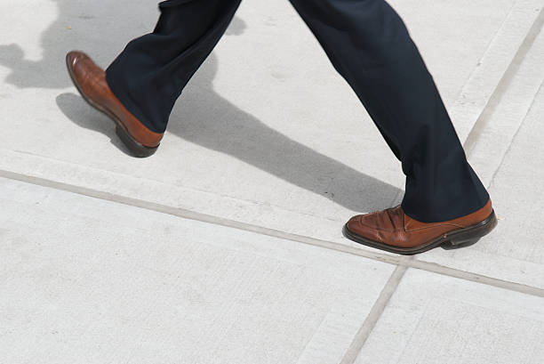 biznesmen brązowy buty czarne spodnie chodzenie na chodniku - business human foot shoe men zdjęcia i obrazy z banku zdjęć