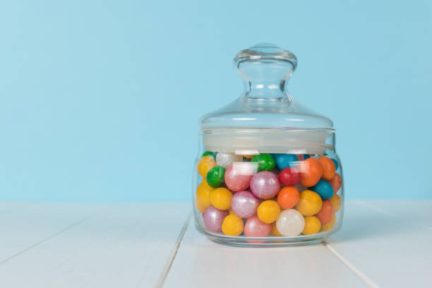 istock A closed glass jar with colorful sweets on a white wooden table. 1728791037