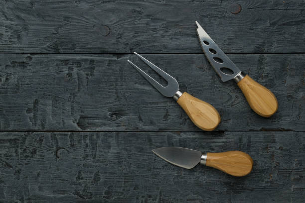 istock Small cheese knives on a dark wooden table. 1728791043