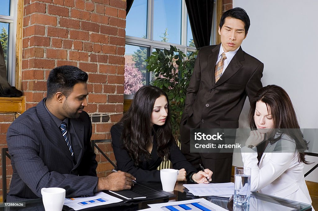 Business meeting Four office employees looking over charts at a business meeting. Adult Stock Photo